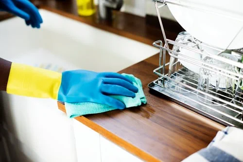 Gloved hands wiping a kitchen countertop during weekly recurring house cleaning in New Jersey
