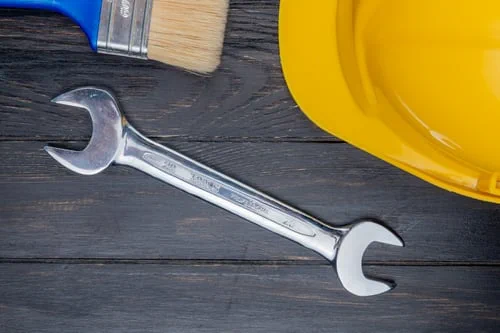 Wrench, paintbrush and hard hat on dark wood — building maintenance and cleaning services in New Jersey