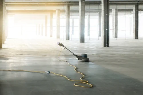 Floor buffing machine polishing concrete in an empty building after construction — post-construction cleaning services in New Jersey.